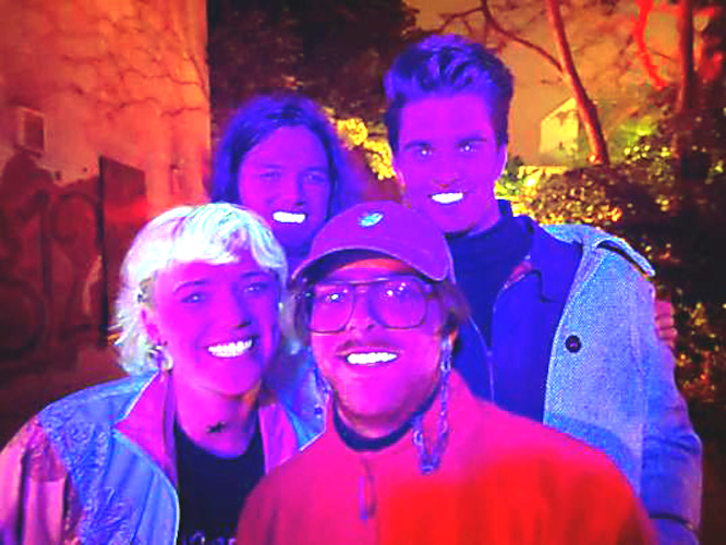 Gruppenfoto bei Schwarzlicht, das dazu führt, dass Augen und Zähne der Bandmitglieder leuchten