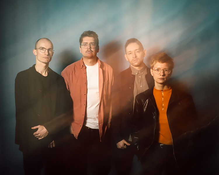 Gruppenfoto der ernst blickenden Bandmitglieder mit leichter Verfemdung