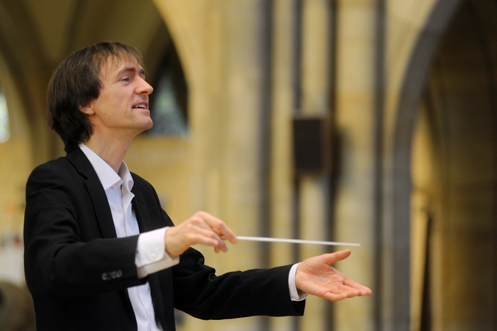 Foto von David Timm mit einem Taktstock in einer Kirche