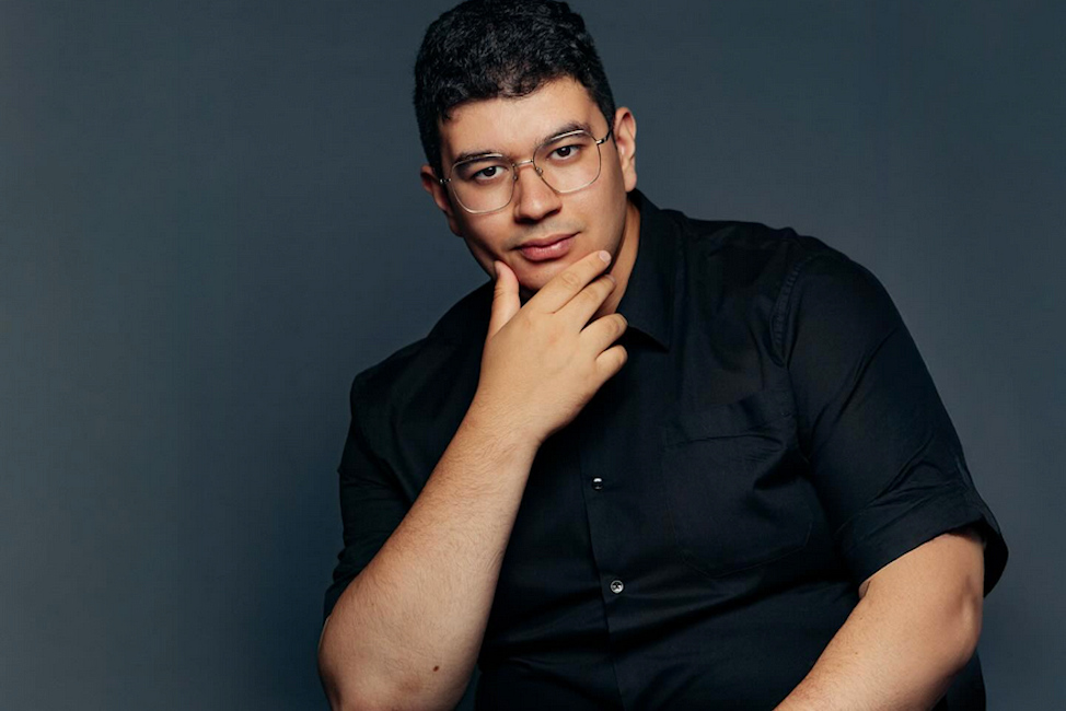 Portraitfoto des Pianisten, der mit einer Hand am Kinn nachdenklich in die Kamera blickt