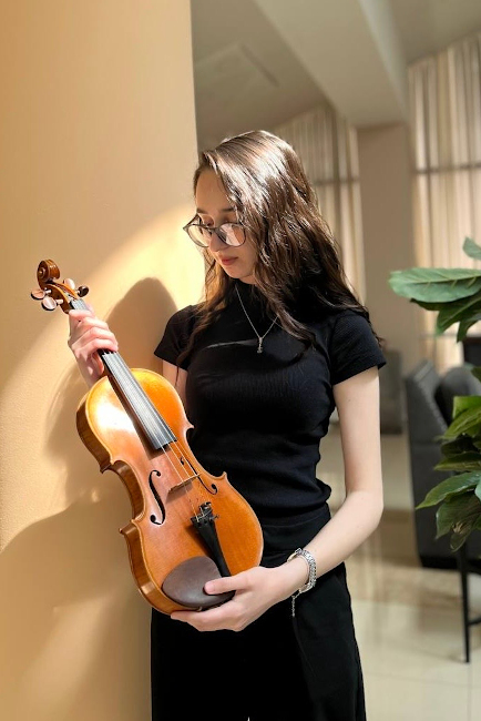 Foto der Musikerin in langem schwarzen Kleid, die ihre Geige präsentiert