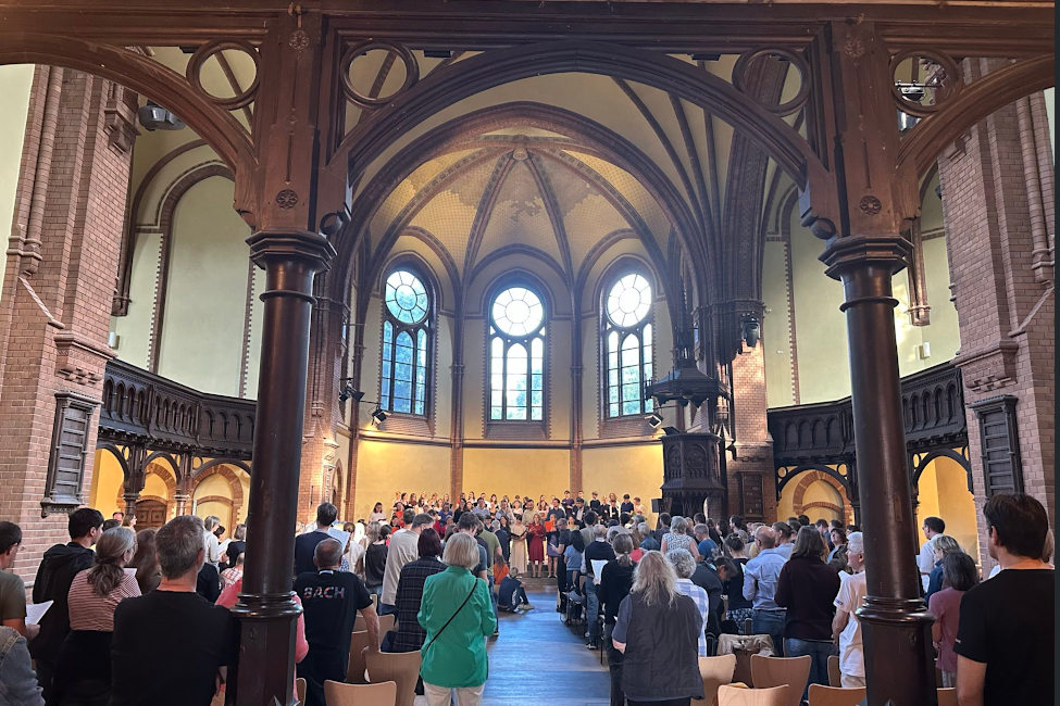 In einer Kirche singen viele Menschen stehend bei einem Chorchonzert mit