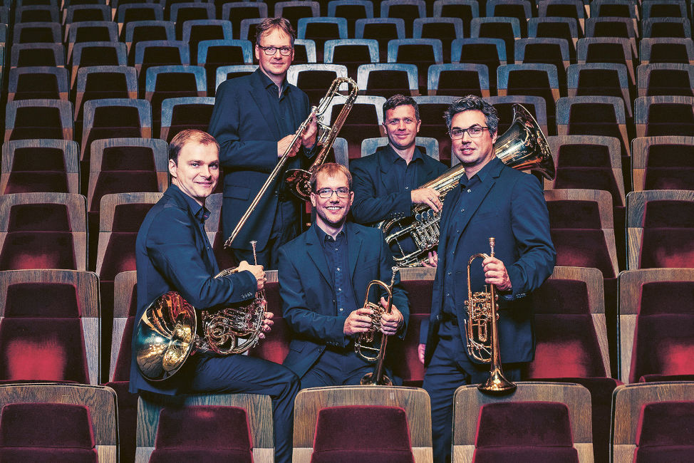 Gruppenfoto der fünf Musiker mit ihren Instrumenten zwischen den Stuhlreihen im Gewandhaus