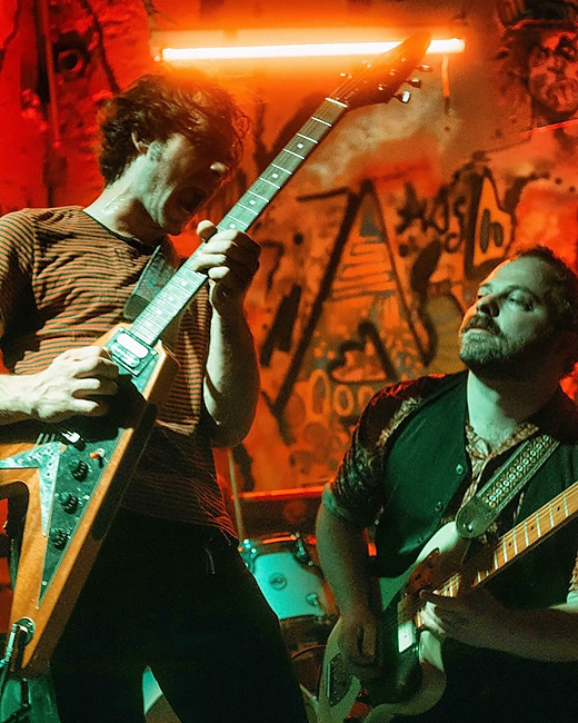 Foto der beiden Gitarristen der Band bei einem Konzert.