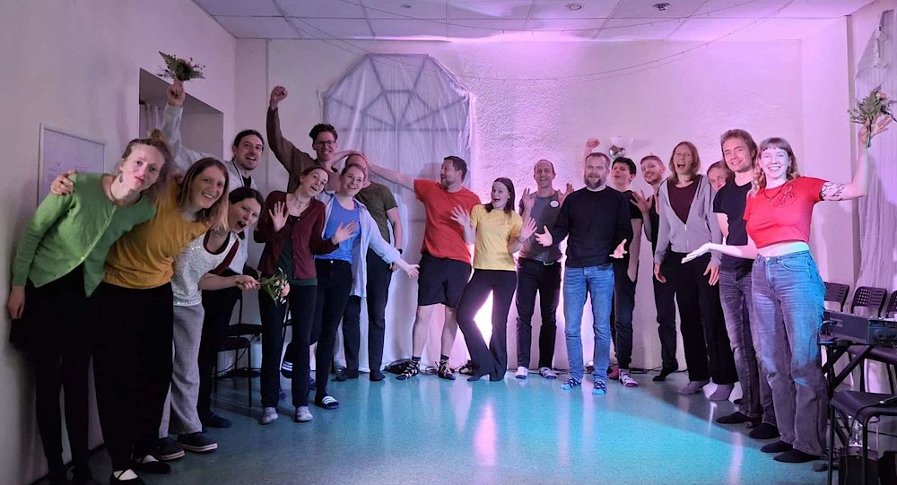 Gruppenfoto von vielen fröhlichen Spielerinnen und Spielern auf einer kleinen, ebenerdigen Bühne