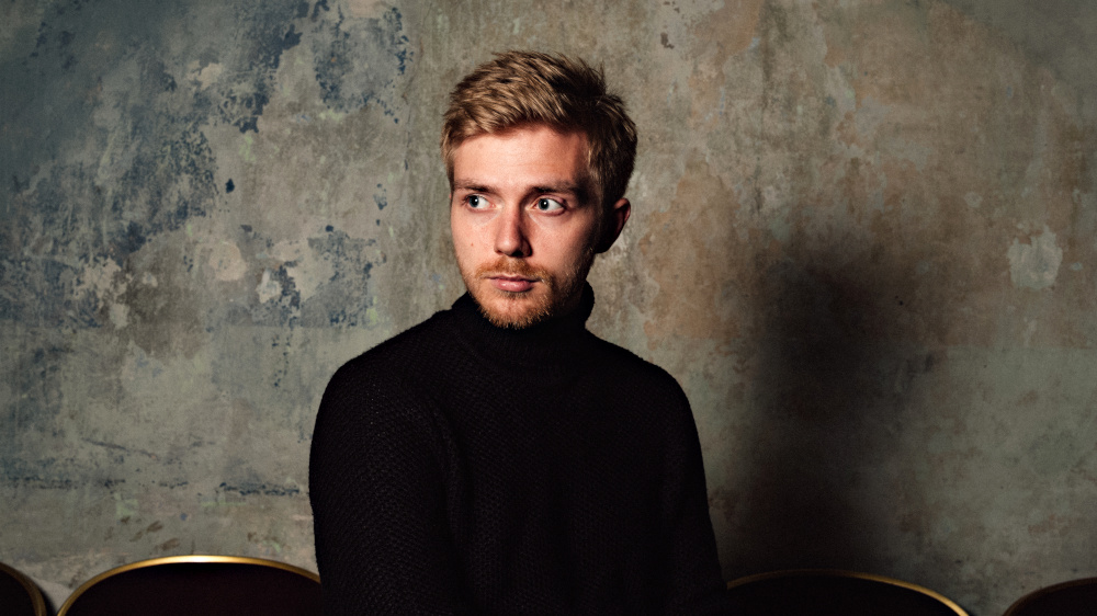 Portraitfoto des ernst blickenden Pianisten im schwarzen Rollkragenpullover