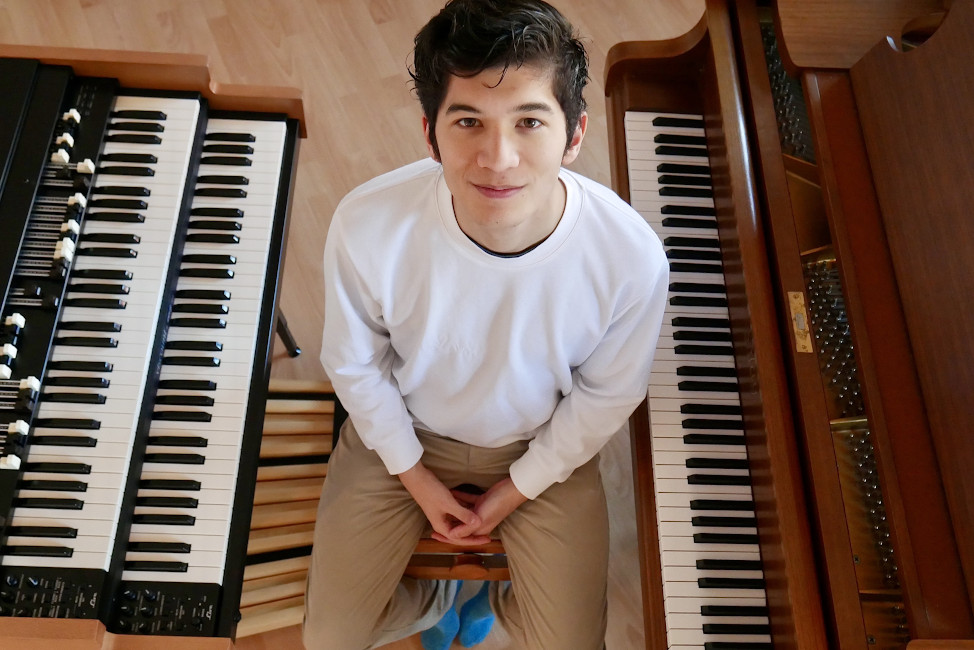 Foto des Musikers von oben, zwischen einem Klavier und einem Keyboard