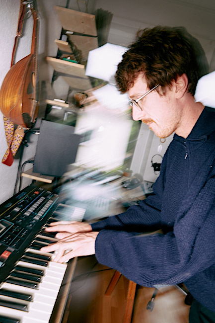 Foto des Musikers, der in einem Zimmer sitzt und auf einem Keyboard spielt