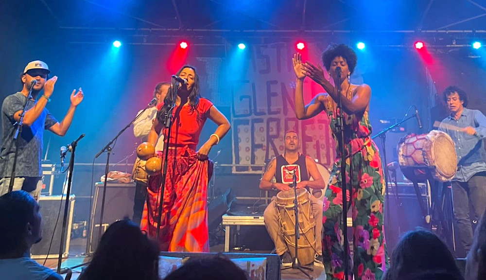 Das Enbsemble mit zwei farbenfroh gekleideten Sängerinnen und vier Percussionisten bei einem Konzert