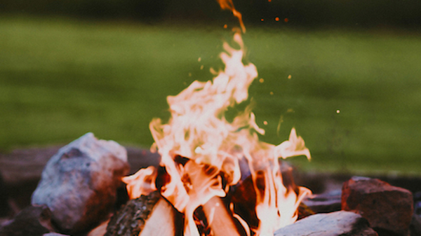 Ein kleines Lagerfeuer in einem Steinkreis auf einer Wiese