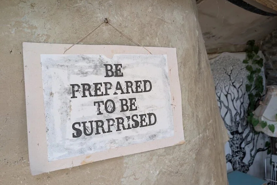 An einer Wand hängt ein Schid mit der Aufschrift "Be PREPARED TO BE SURPRISED".