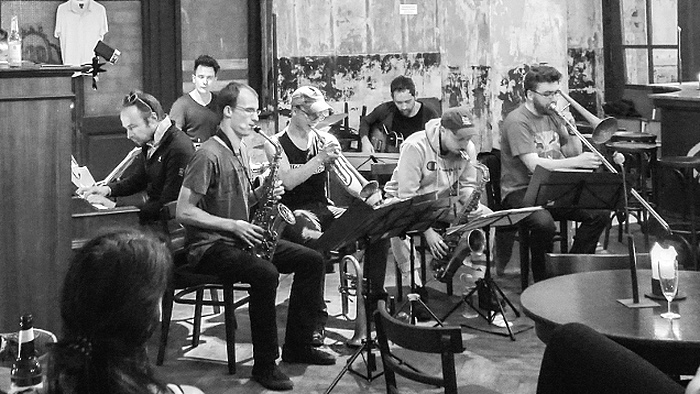 Schwarz-Weiß-Foto: die Musiker des Real Jazz Orchestras musizieren miteinander