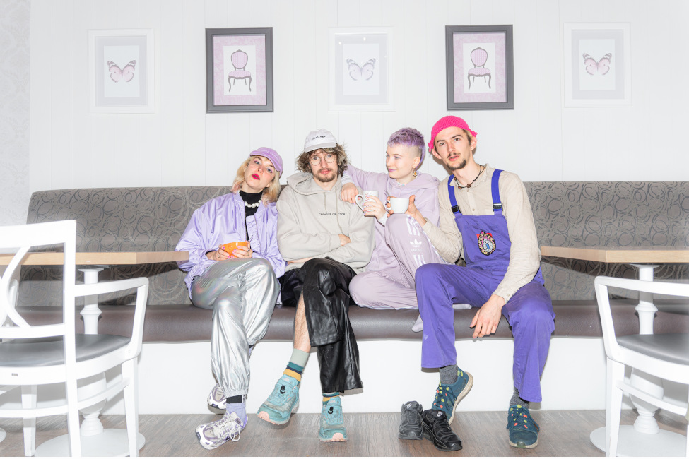 Gruppenfoto der Band auf einer Bank in einem Café