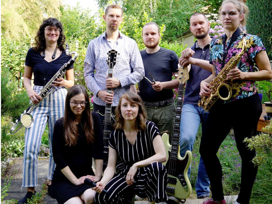 Gruppenfoto der Band mit ihren Instrumenten in einem grünen Garten