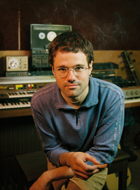 Foto des Musikers vor einem Tisch mit Keyboards und anderen elektronischen Geräten