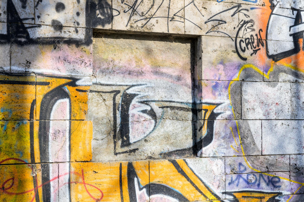 Eine Mauer aus Natursteinen ist mit Graffiti bedeckt.