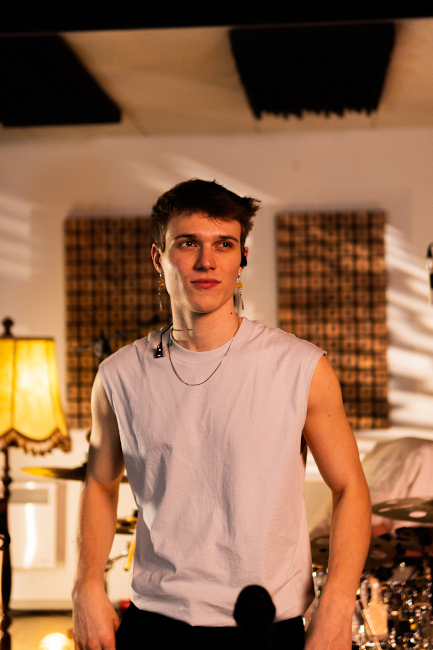 Foto des sympathisch blickenden Künstler im ärmellosen Shirt in einem Studio