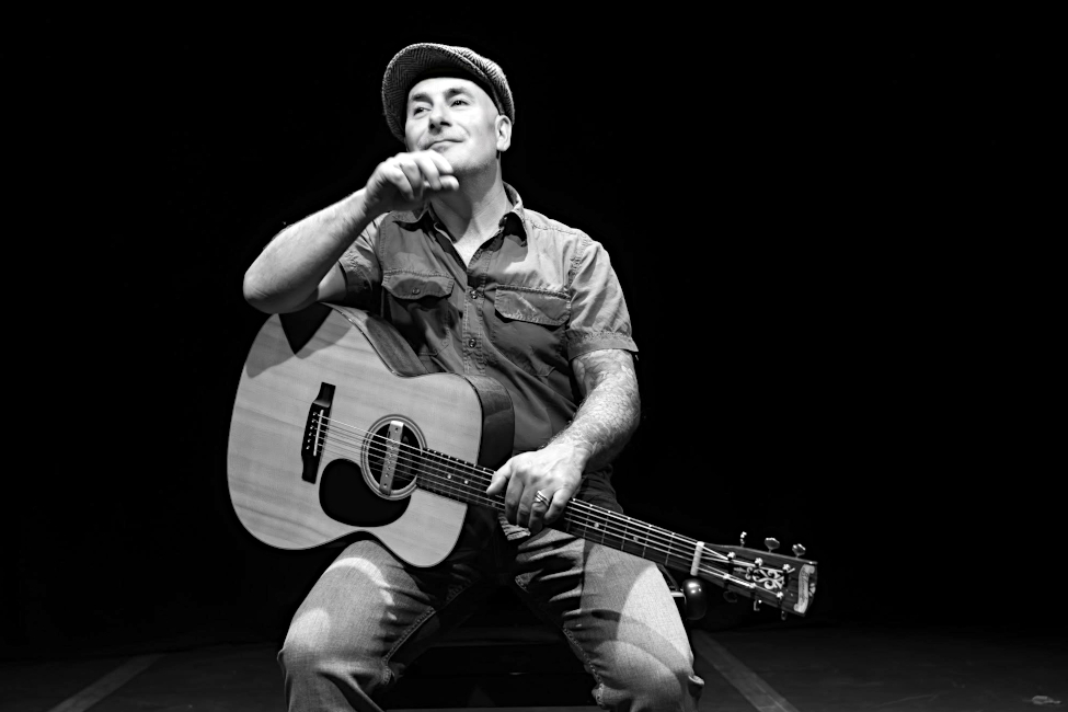 Schwarz-Weiß-Foto des Musikers mit Gitarre und nachdenklichem Gesichtsausdruck
