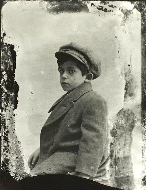 Historisches Foto eines kleinen Jungen in dickem Mantel und mit Schiebermütze