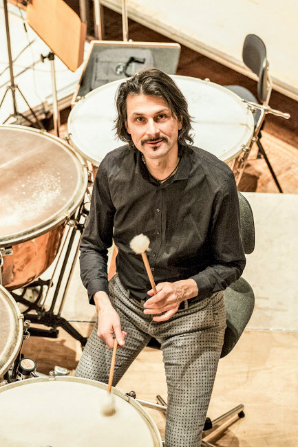 Stefan Rapp sitzt auf einer Bühne und spielt auf vier Kesselpauken.