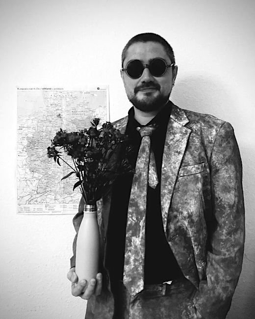 Foto des Musikers mit einer großen Sonnenbrille und einer Vase mit Rosen in der Hand