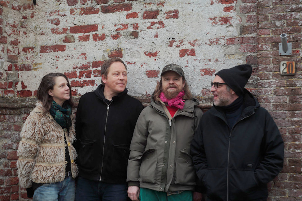 Gruppenfoto der Band in Winterkleidung vor einer Ziegelmauer